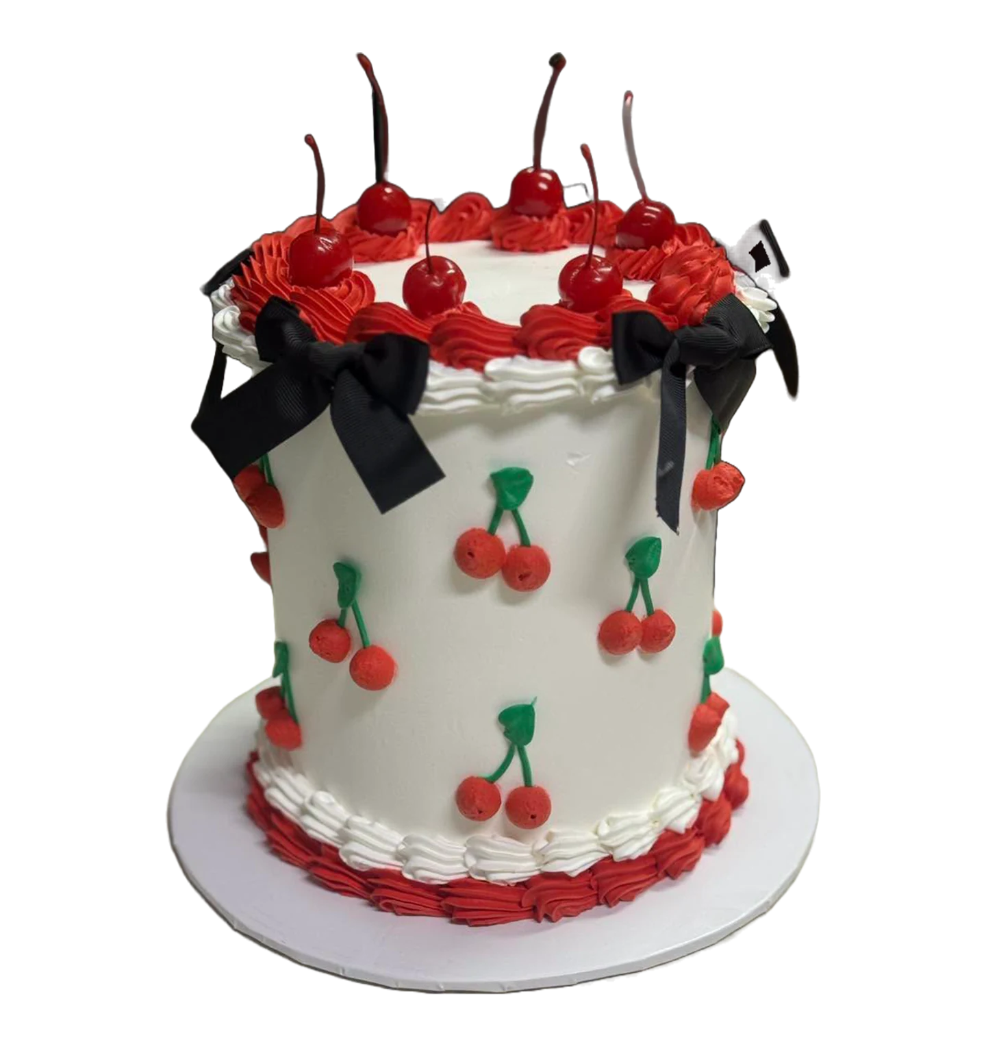 Pastel blanco con cerezas rojas, crema roja y moños negros